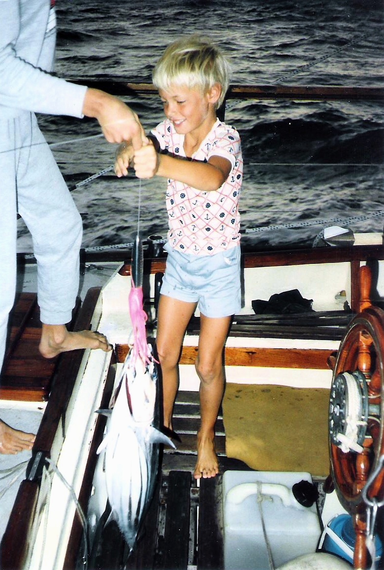 Antony in the cockpit holding up a string of tuna.